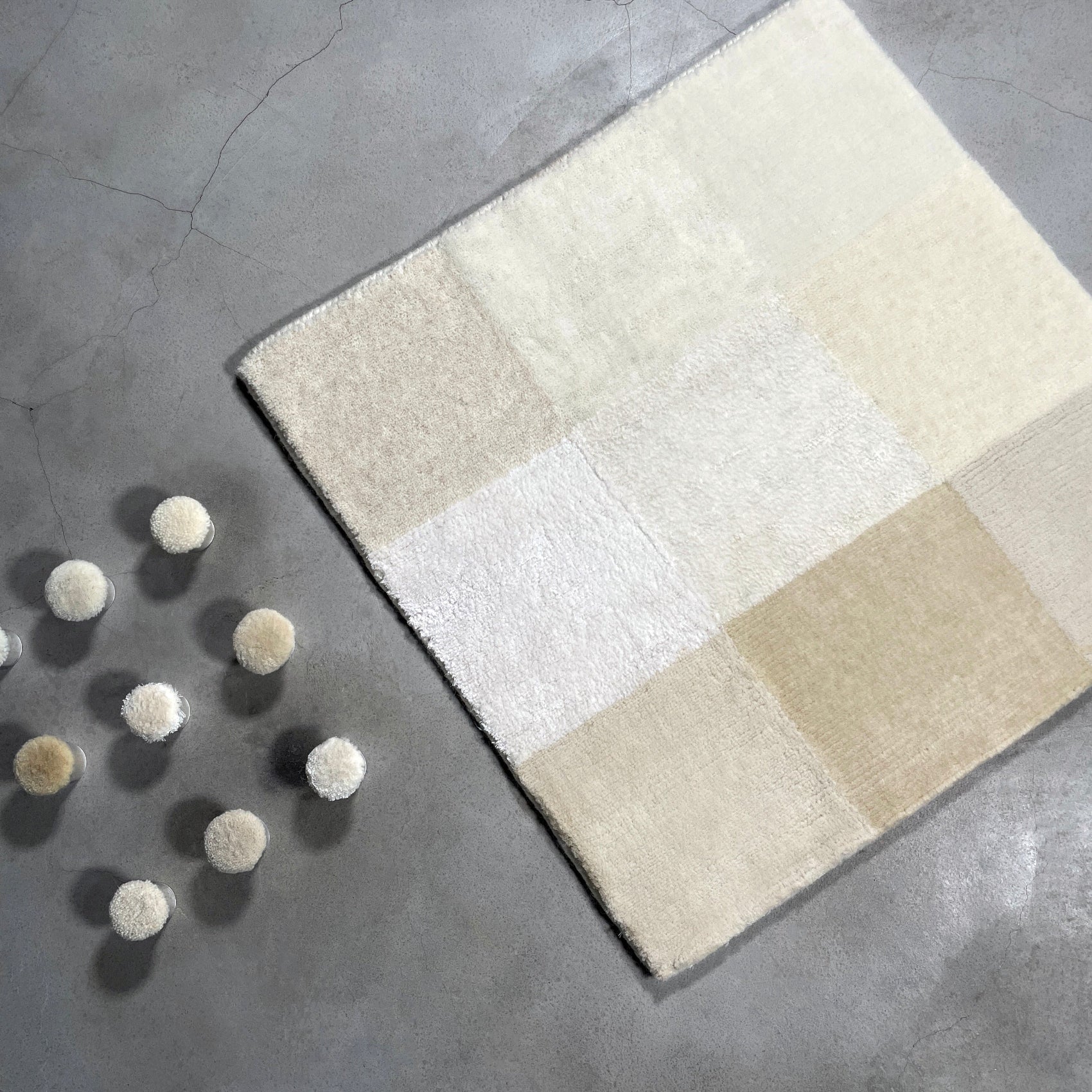 Beige and white checkered rug on a gray concrete floor with decorative balls.